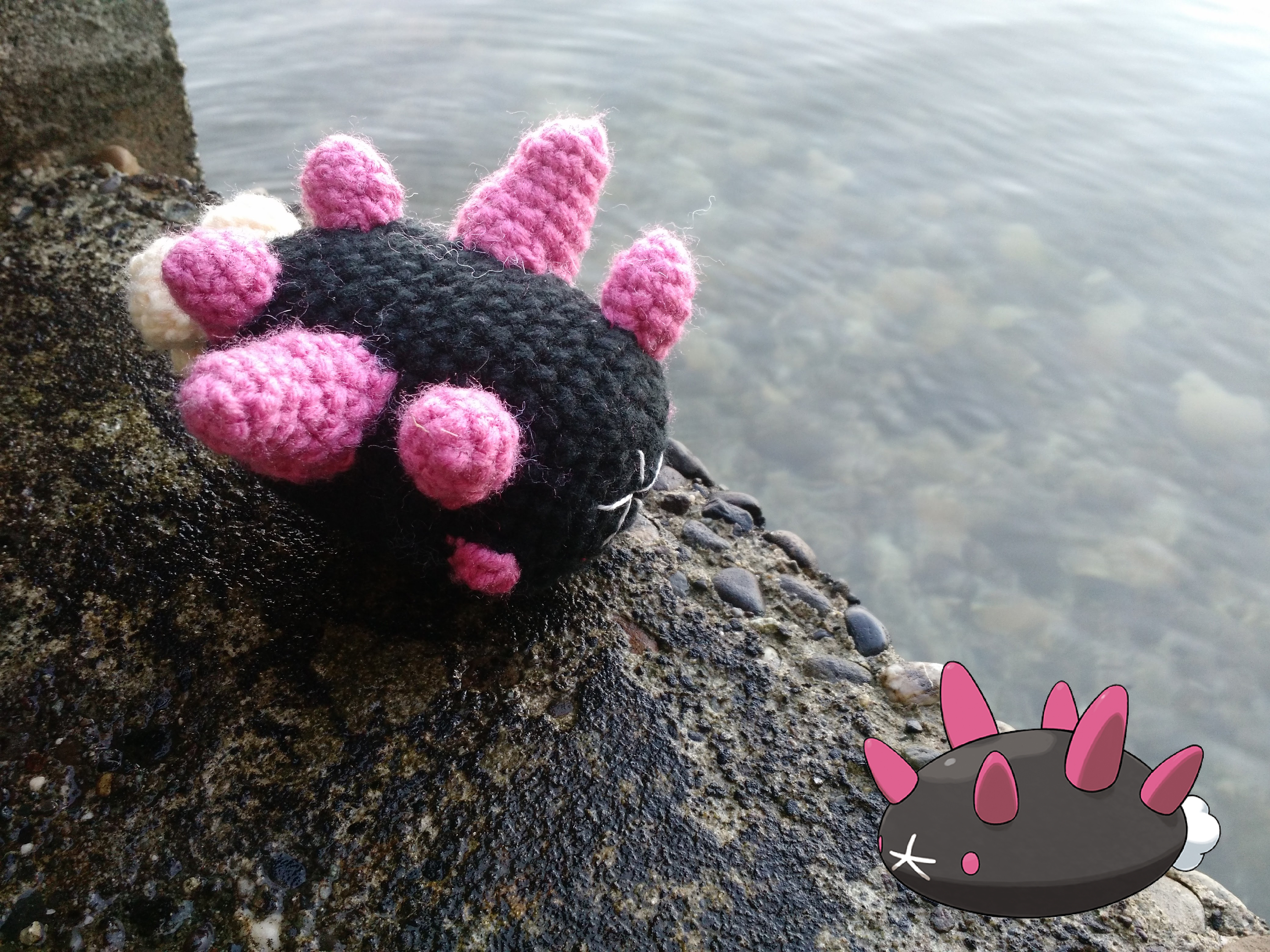 Photo of a crochet stuffed toy version of the Pokemon Pyukumuku sitting on a dock, with an icon showing the official art in the lower right corner.